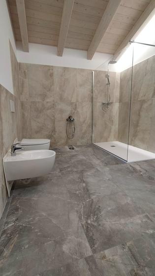 Bagno in mansarda con soffitto in legno a vista, sanitari sospesi e doccia walk-in con piatto a filo