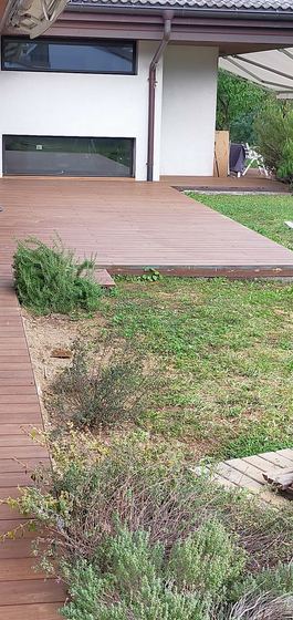 Bordo del decking che si raccorda con l'aiuola e il prato, con il profilo di chiusura in vista