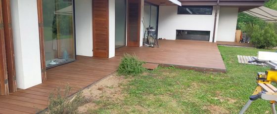 Decking posato davanti alle porte finestre del porticato, che prosegue a lato della casa fino al prato