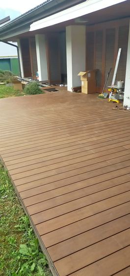 Ampia superficie di decking appena posata davanti al porticato, con le scatole del materiale ancora in opera