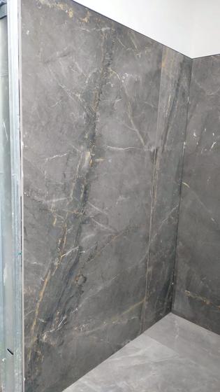 Dettaglio di due lastre in gres effetto marmo grigio con venature dorate, con la venatura che prosegue da una lastra all'altra