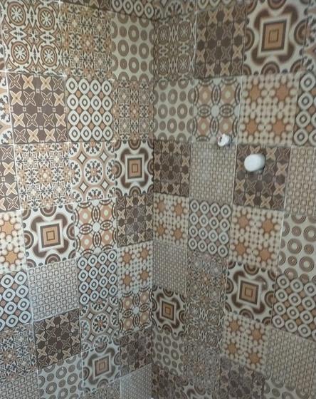 Parete di doccia rivestita con piastrelle quadrate decorate a fantasia geometrica, con raccordo d'angolo continuo