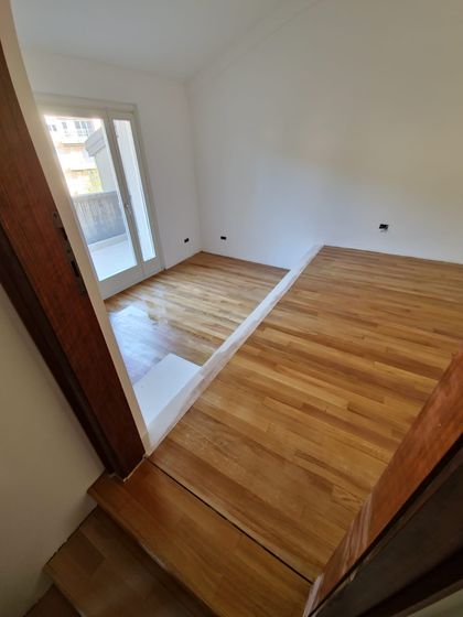 Pavimento in legno a listoncini rifinito, ripreso dai gradini in legno che salgono alla stanza
