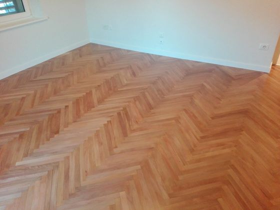 Stanza vuota appena finita, con pavimento in legno chiaro a spina di pesce e pareti bianche