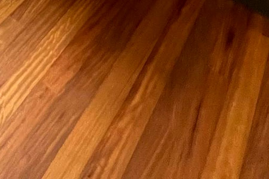Pavimento in legno rifinito, con la venatura in evidenza e un riflesso morbido di luce