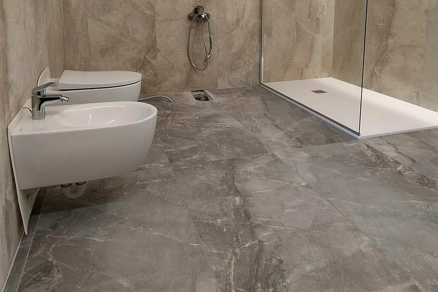 Bagno finito con doccia a filo pavimento, sanitari sospesi e pavimento in gres effetto marmo